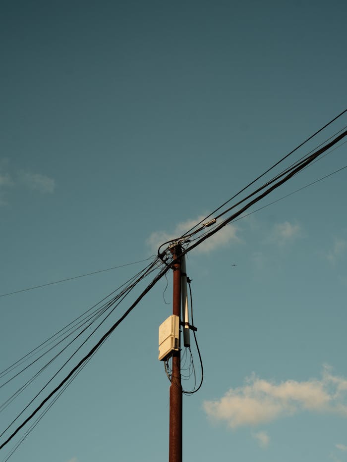 A single utility pole with power lines under a clear blue sky, signifying infrastructure and electricity.